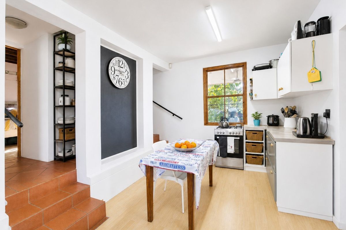 A functional kitchen featuring built-in cabinetry, a gas stove, and oven, with tiled steps leading to an adjacent living area.