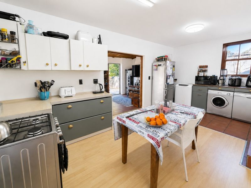 A functional kitchen featuring a mix of white and grey cabinetry, gas stove, and integrated laundry space with direct access to an adjacent room.