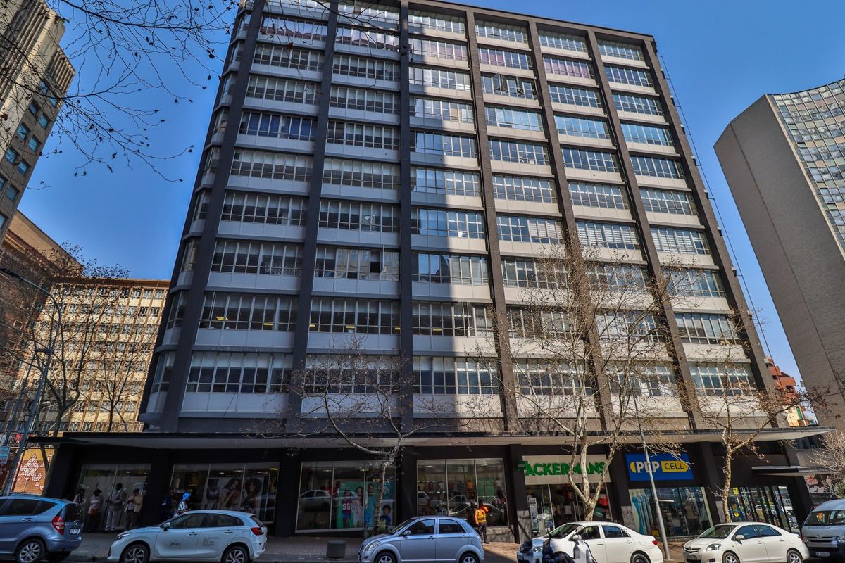 A multi-story commercial building featuring a grid-pattern facade with extensive glazing and ground-level retail storefronts in an urban setting.
