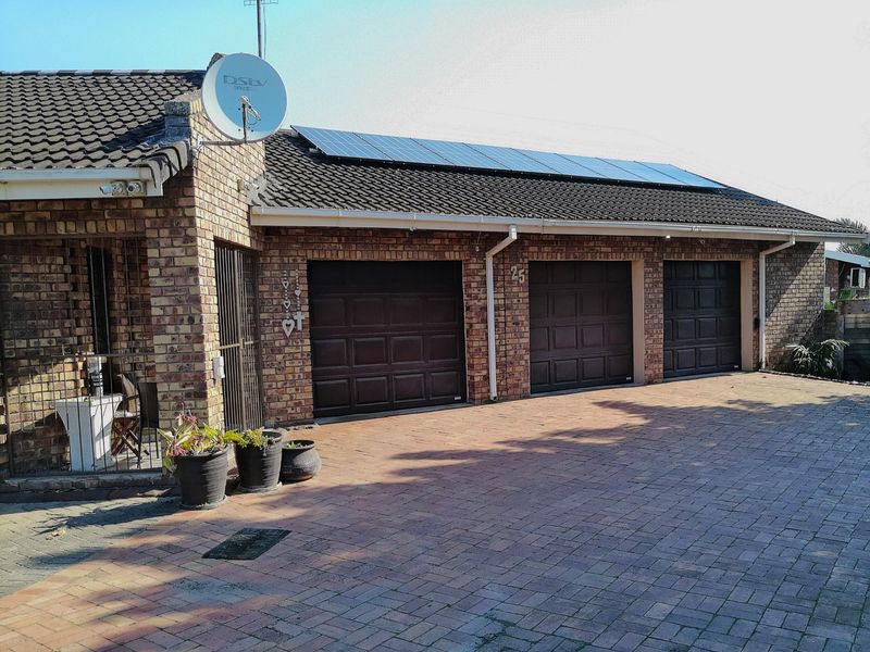 A well-maintained brick exterior featuring a triple garage, solar panel installation on the tiled roof, and a paved driveway.