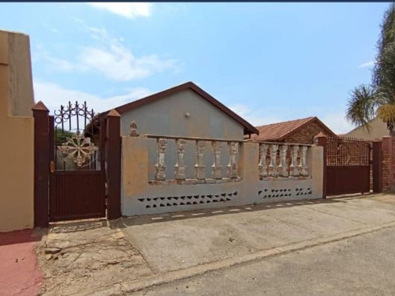 Front exterior view of the property featuring a gated entrance, concrete balustrade boundary wall, and tiled roof structure.