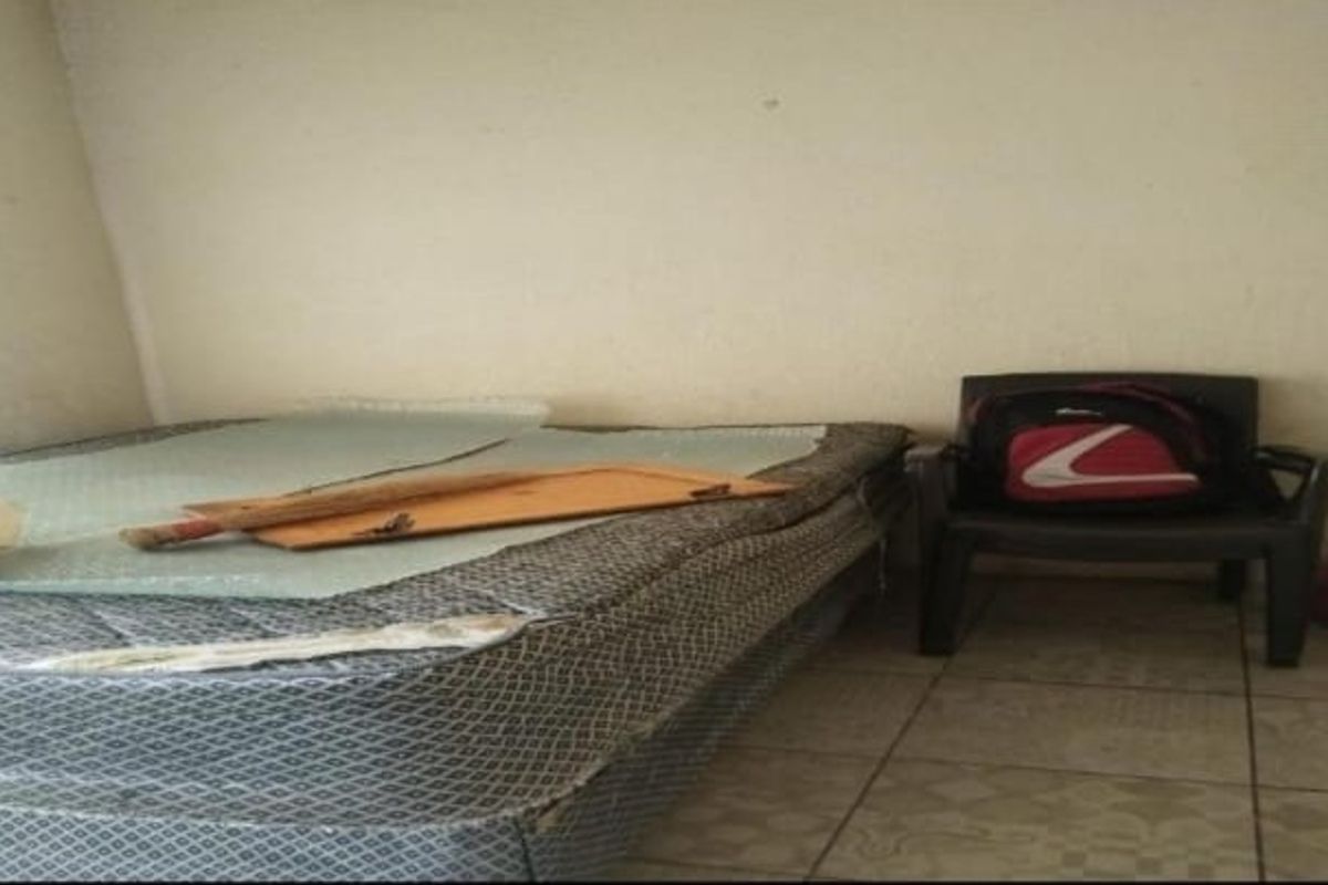 A bedroom space featuring tiled flooring and plain walls, currently requiring cosmetic updates and maintenance to improve its overall condition.