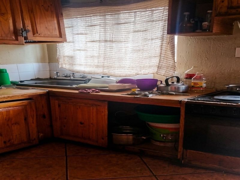 A dated kitchen featuring wooden cabinetry, a built-in oven, and tiled flooring, offering potential for a modern renovation.