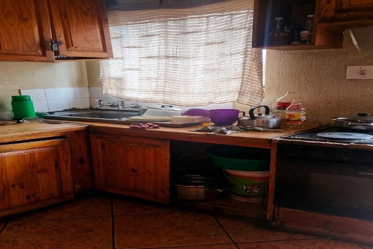 A dated kitchen featuring wooden cabinetry, a built-in oven, and tiled flooring, offering potential for a modern renovation.
