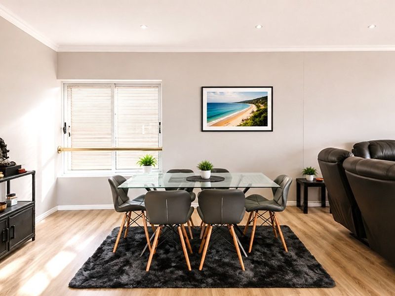 A bright and well-maintained open-plan living and dining area featuring modern laminate flooring and recessed downlighting.