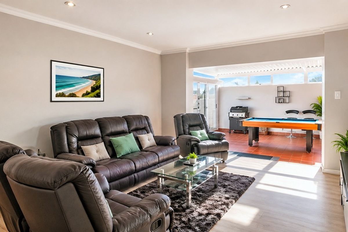 Spacious open-plan living area featuring laminate flooring, recessed lighting, and seamless transition to a covered tiled patio area.