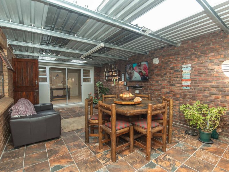Covered patio area featuring exposed brick walls, tiled flooring, and a corrugated metal roof, providing a versatile outdoor entertainment space.
