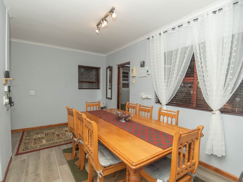 A functional dining room featuring tiled flooring, track lighting, and window blinds, providing a practical space for family meals.