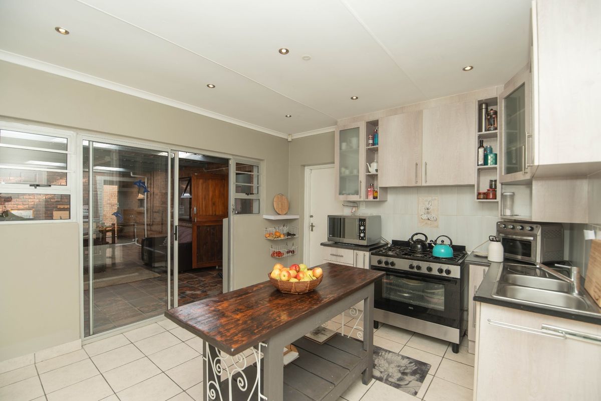 Functional kitchen featuring built-in cabinetry, a gas stove with oven, double sink, and direct access to an enclosed patio area through sliding glass doors.