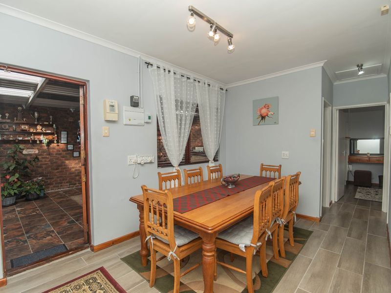 A functional dining room featuring tiled flooring, track lighting, and direct access to an adjacent covered patio area.
