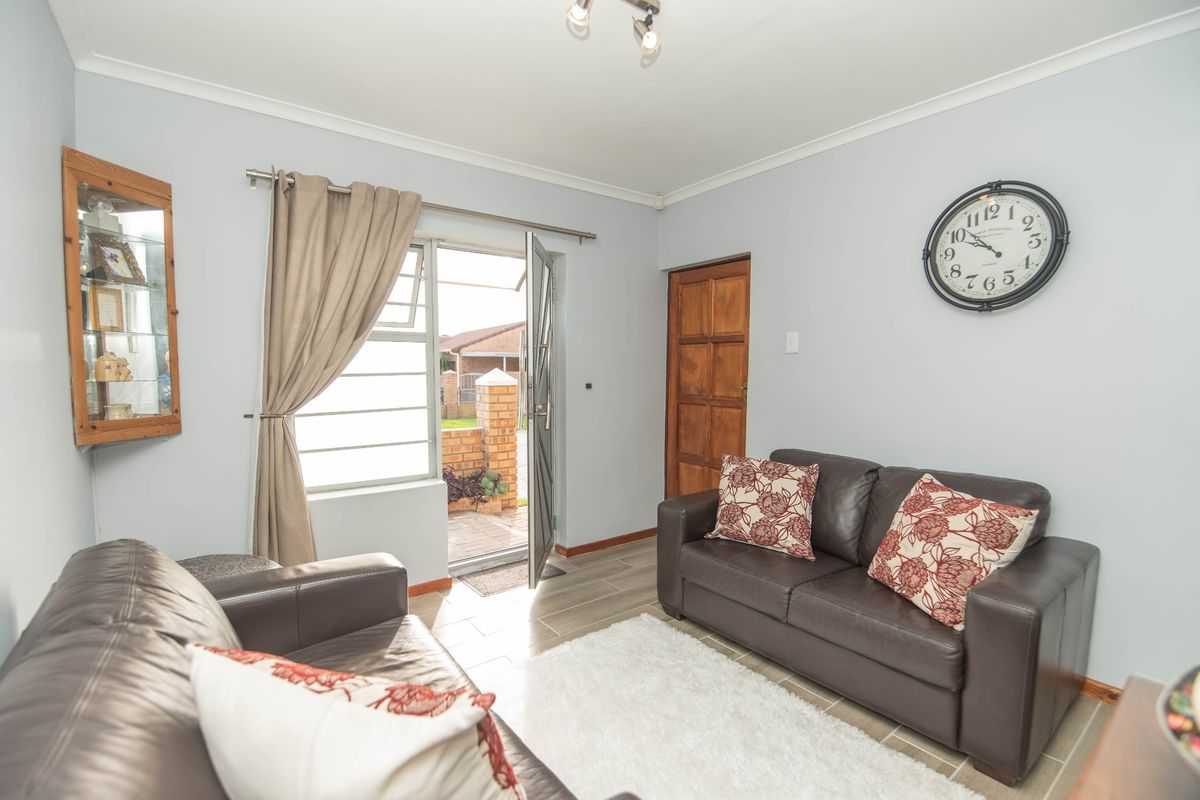 A living room featuring tiled flooring, coved ceilings, and direct access to an outdoor area through a glass-paneled door.