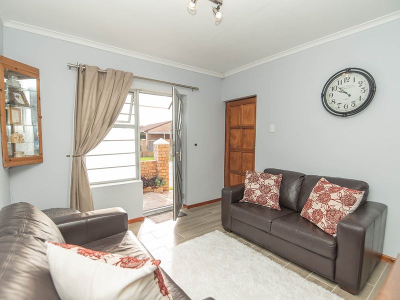 A living room featuring tiled flooring, coved ceilings, and direct access to an outdoor area through a glass-paneled door.
