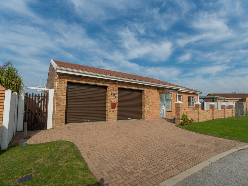 A well-maintained single-story brick house featuring a double garage, paved driveway, and secure perimeter walling in a neat residential setting.