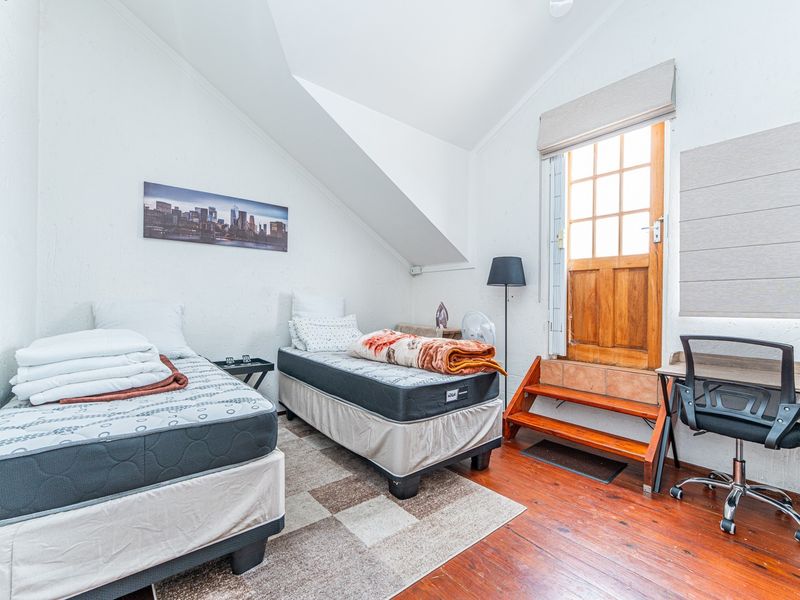 Bedroom featuring timber flooring, sloped ceilings, and direct access to an outdoor area via a timber door.