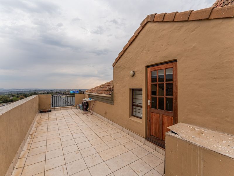 Spacious open-air balcony featuring tiled flooring, a timber-framed door, and panoramic views, offering potential for an inviting outdoor living space.