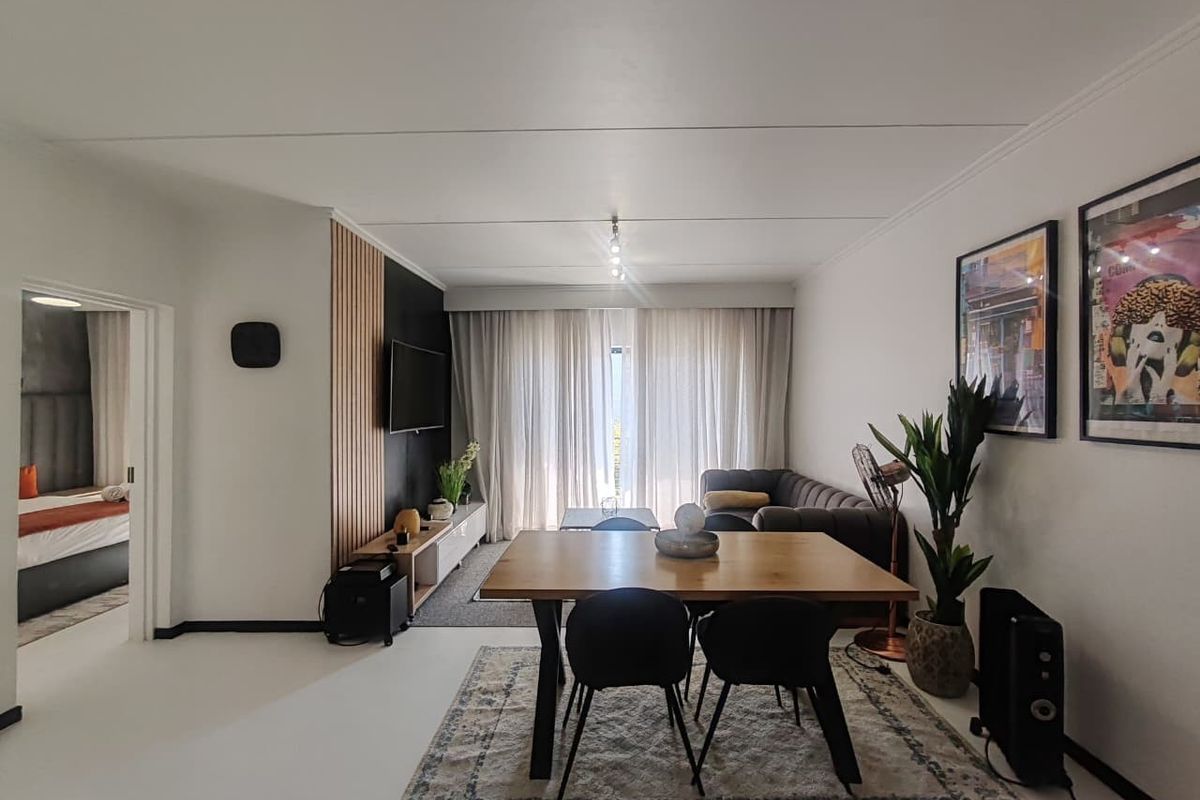 Modern open-plan living and dining area featuring a stylish slatted timber accent wall, neutral flooring, and ample natural light through floor-to-ceiling curtains.