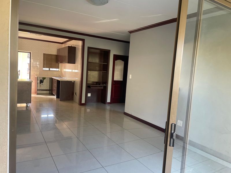 An open-plan living and kitchen area featuring tiled flooring, built-in cabinetry, and a sliding glass door leading to an outdoor space.