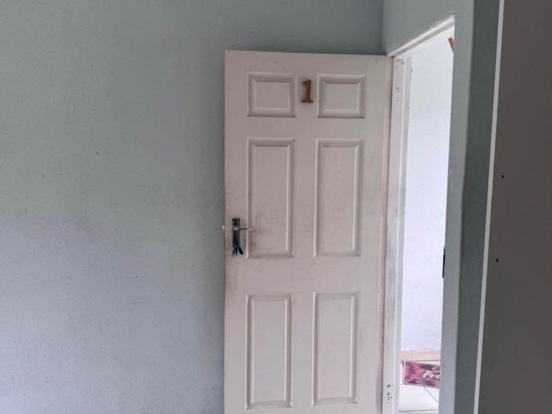 An empty bedroom featuring tiled flooring and a standard panel door, presenting a blank canvas ready for renovation or interior design updates.