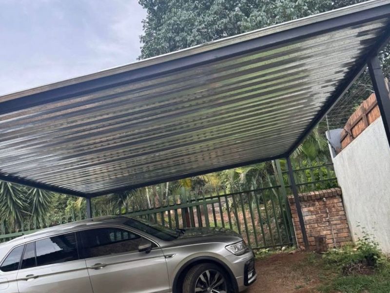 A functional outdoor carport featuring a corrugated metal roof supported by steel posts, providing covered parking space.