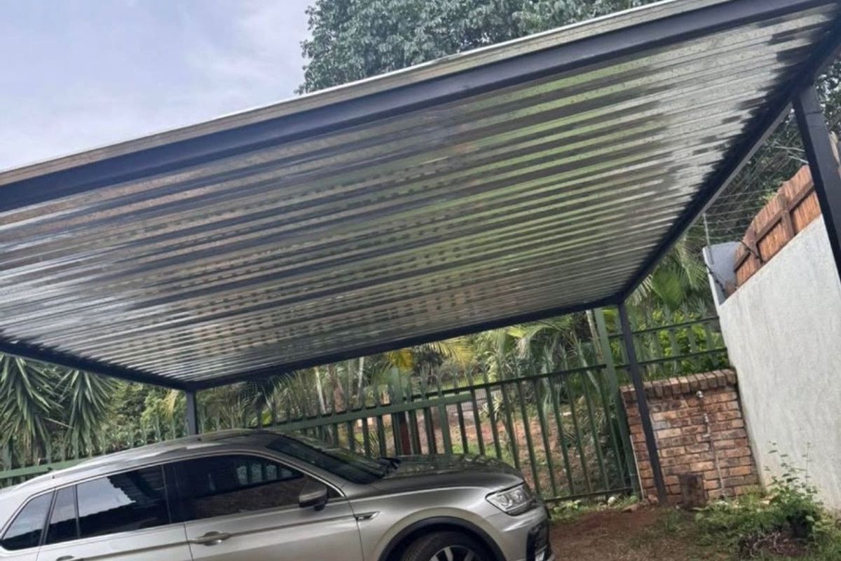 A functional outdoor carport featuring a corrugated metal roof supported by steel posts, providing covered parking space.