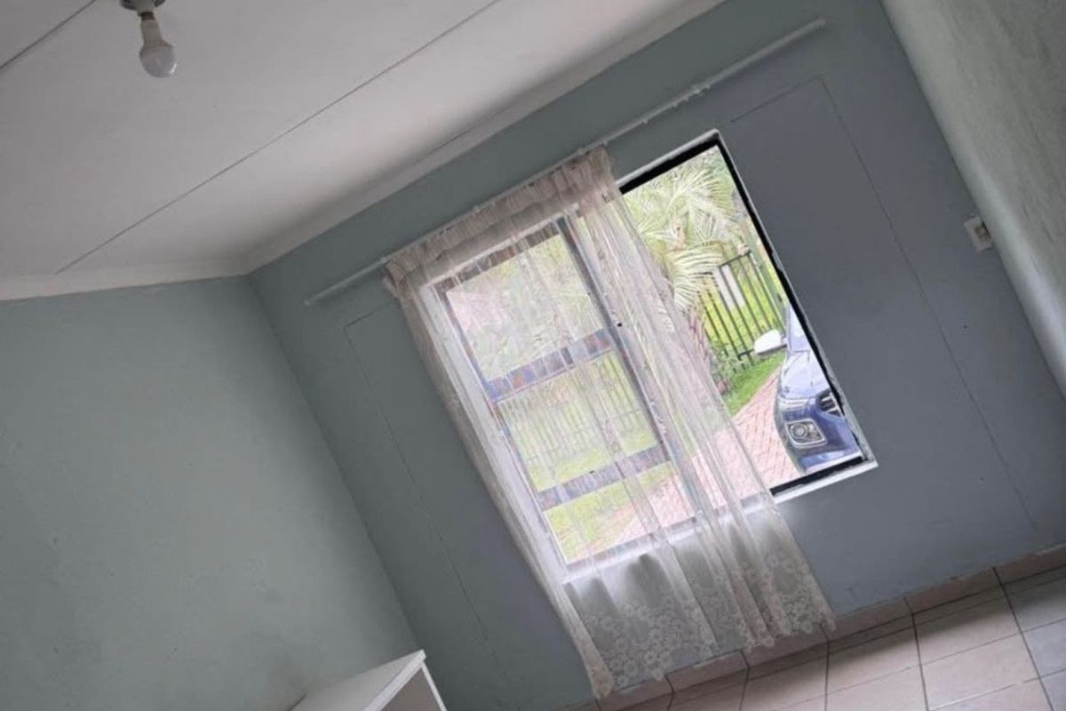 A simple, empty bedroom featuring tiled flooring and a window, providing a blank canvas for potential interior design updates.