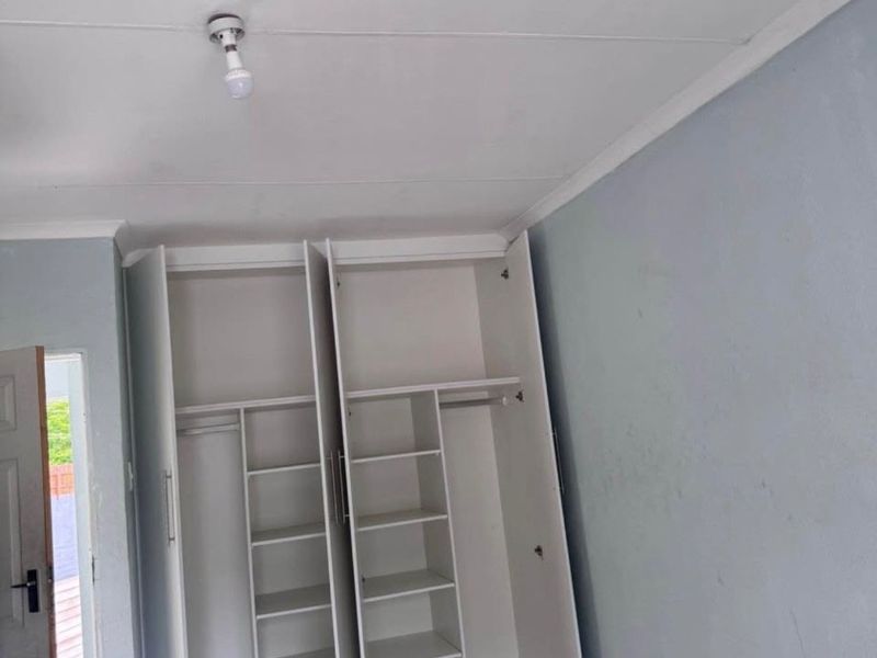 A bedroom featuring built-in cupboards and tiled flooring, presenting a blank canvas ready for personalization.