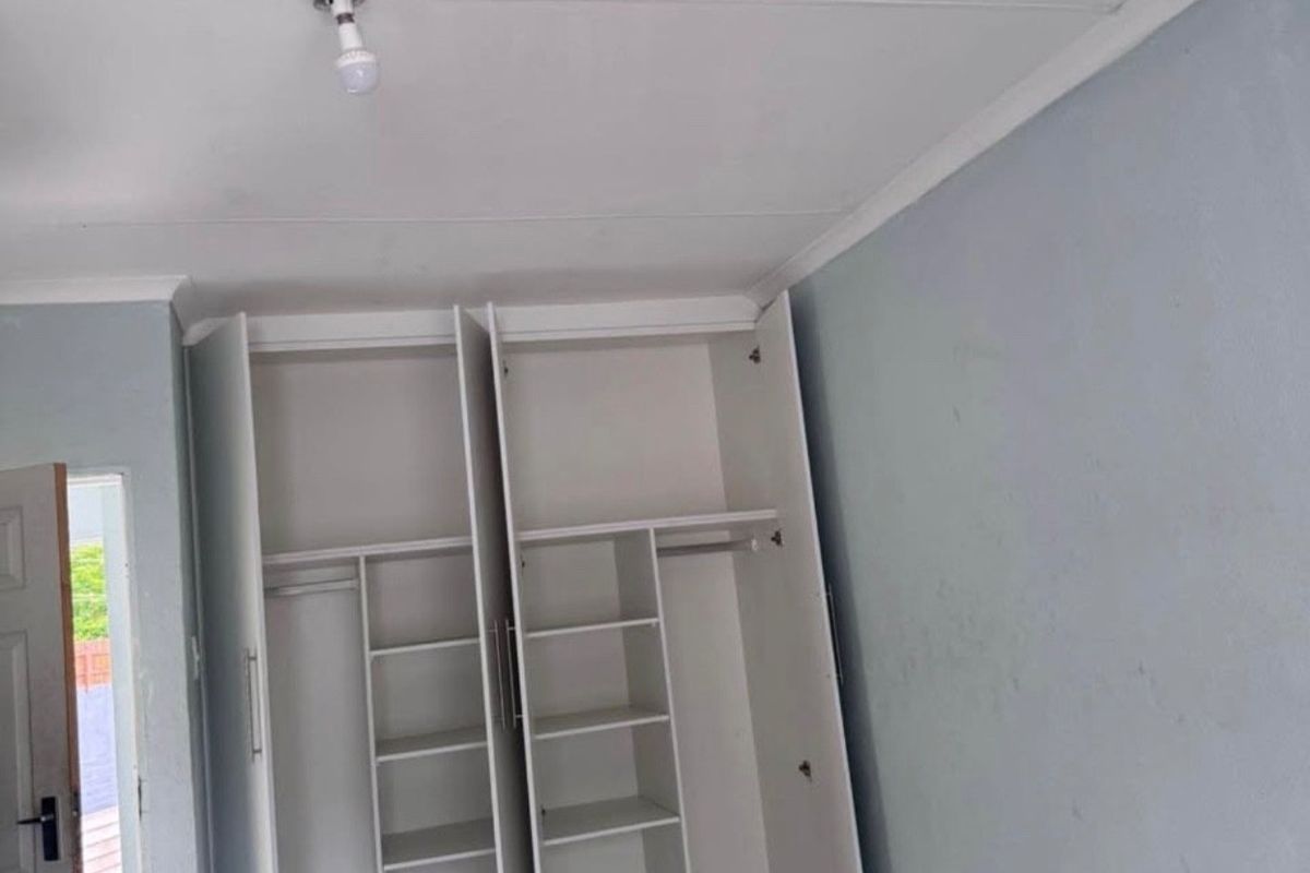 A bedroom featuring built-in cupboards and tiled flooring, presenting a blank canvas ready for personalization.