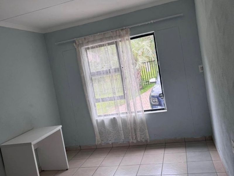 A simple, empty bedroom featuring tiled flooring and a single window, providing a blank canvas for potential interior design updates.