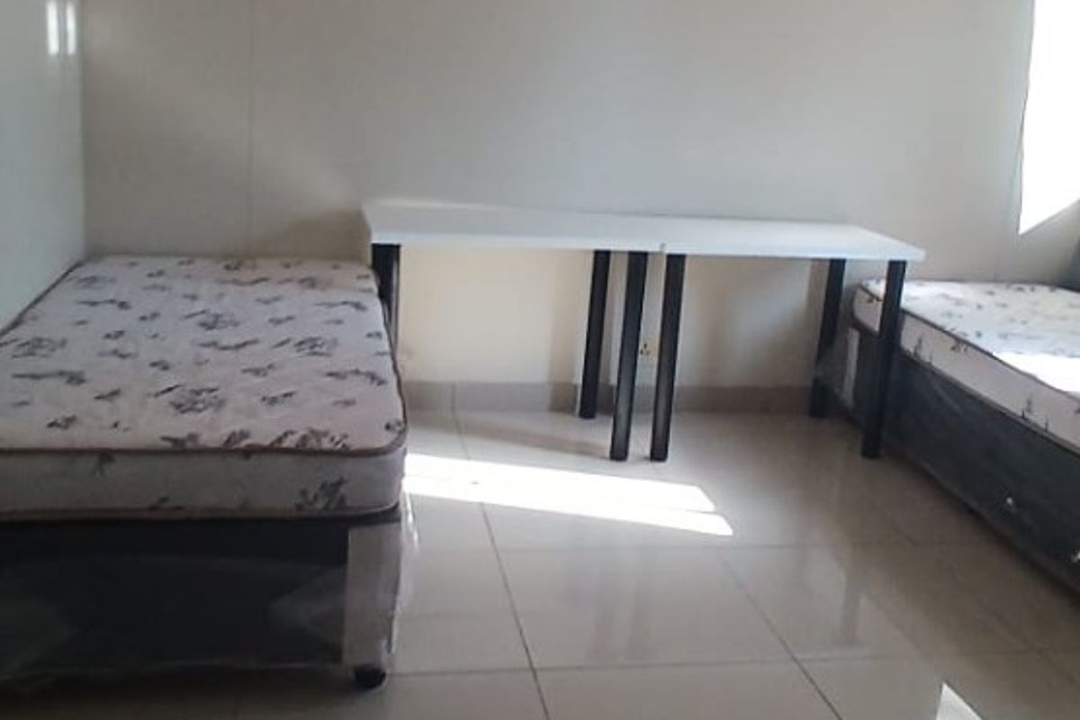 A simple bedroom featuring neutral walls and tiled flooring, providing a functional and clean space.