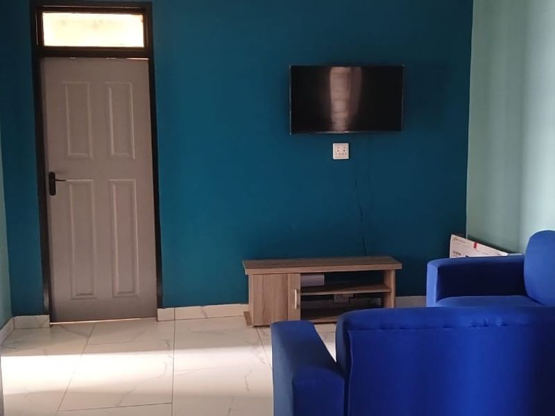 A living room featuring tiled flooring, a blue accent wall, and a panel door with a transom window.