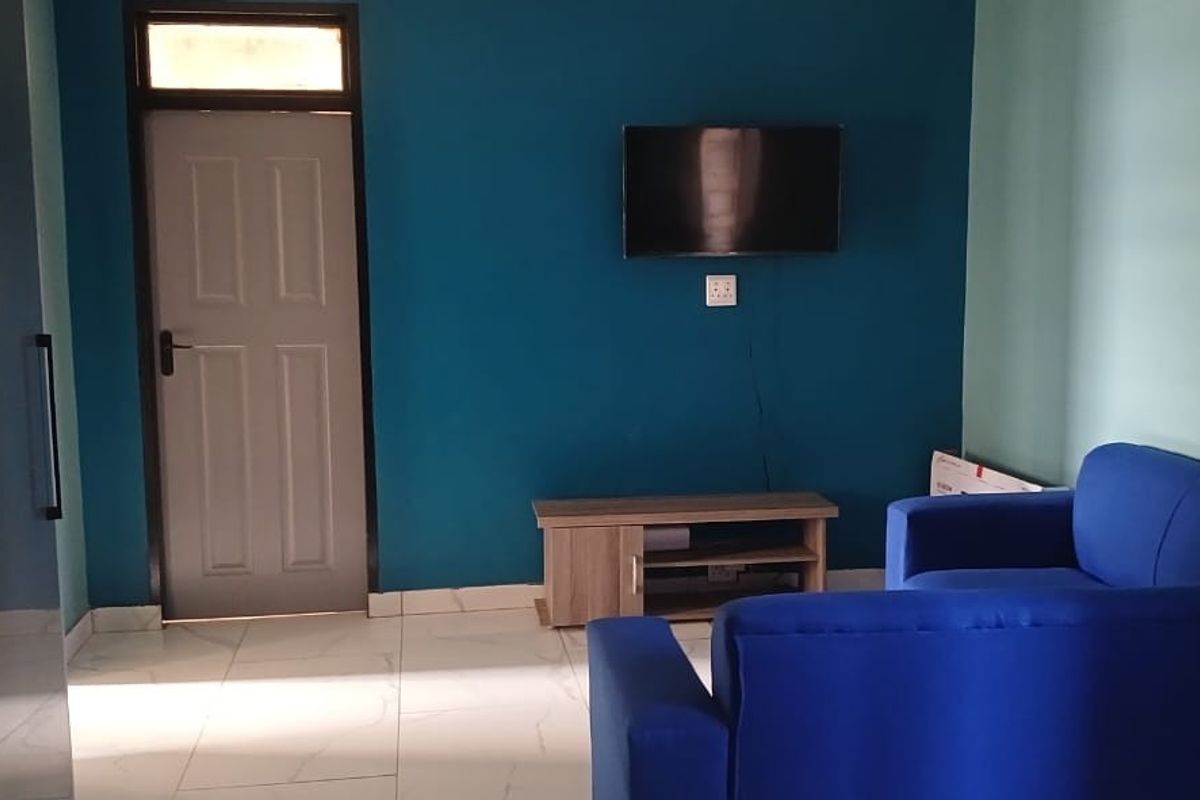 A living room featuring tiled flooring, a blue accent wall, and a panel door with a transom window.