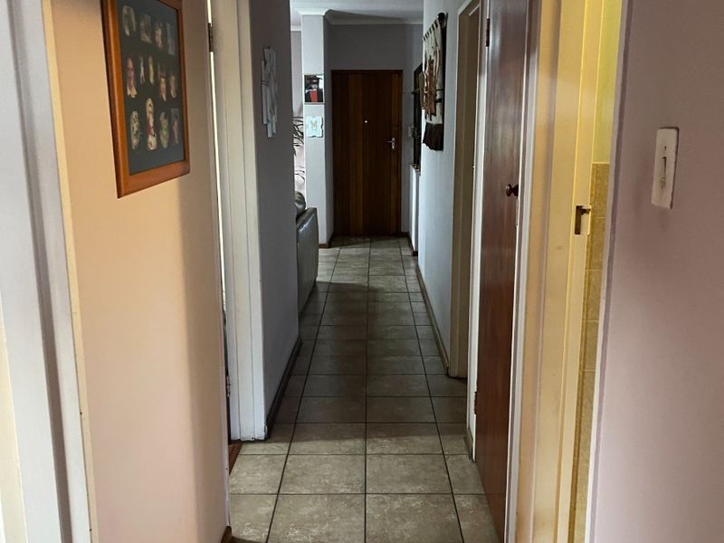 A functional hallway featuring tiled flooring and built-in storage cupboards, providing access to various rooms within the home.