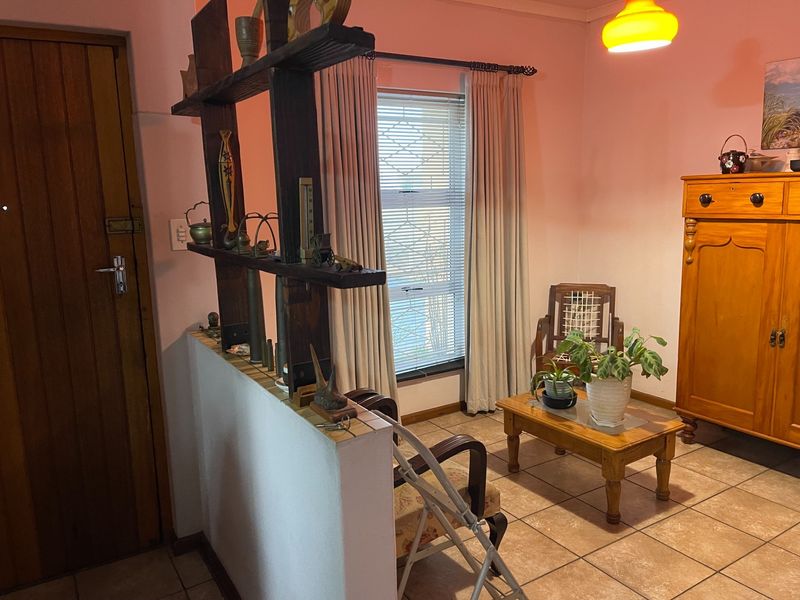 A living area featuring tiled flooring, a timber entrance door, and a built-in wooden room divider, providing a functional and traditional layout.