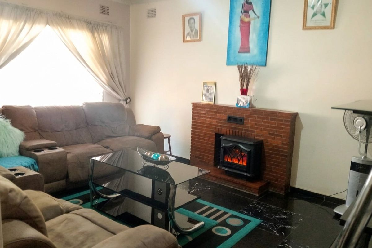 A living room featuring a brick fireplace with an electric insert and dark tiled flooring.