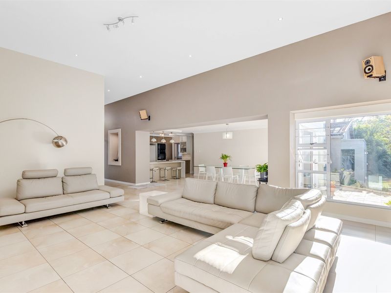 Spacious open-plan living area featuring large format floor tiles, high ceilings with recessed lighting, and a seamless flow into the adjacent kitchen and dining space.