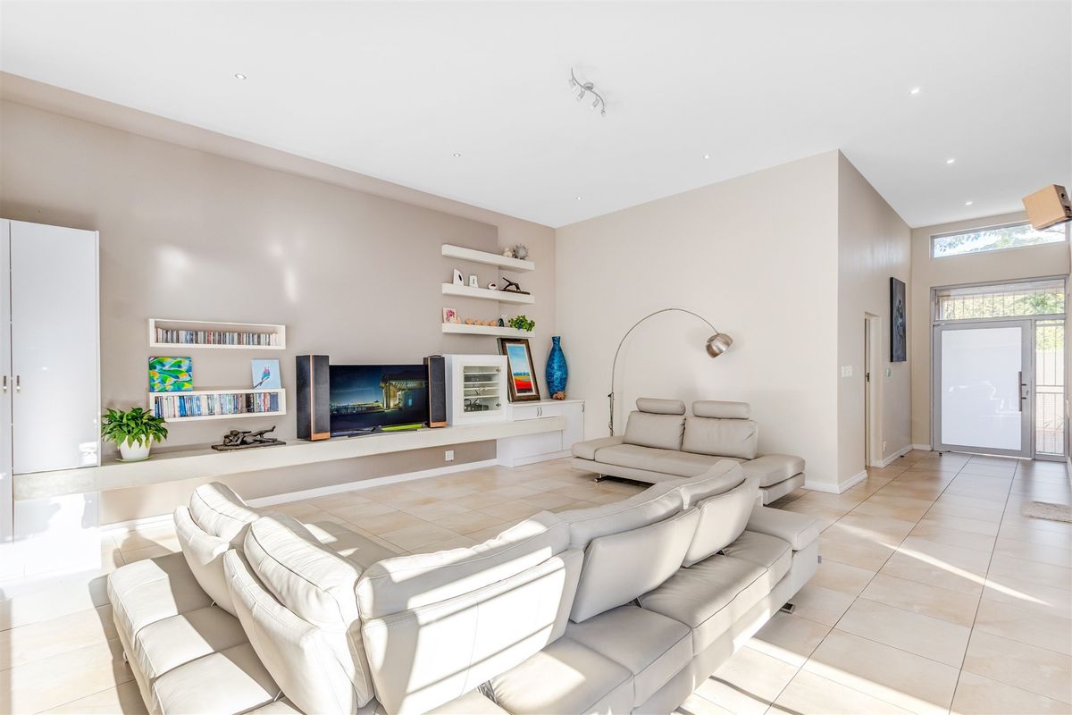 Spacious living room featuring neutral tiled flooring, built-in shelving units, and recessed lighting, creating a bright and open atmosphere.