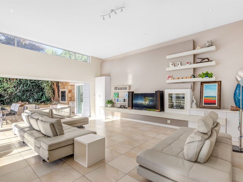 Spacious living room featuring large format floor tiles, built-in cabinetry with shelving, and expansive sliding doors opening to an outdoor patio area.