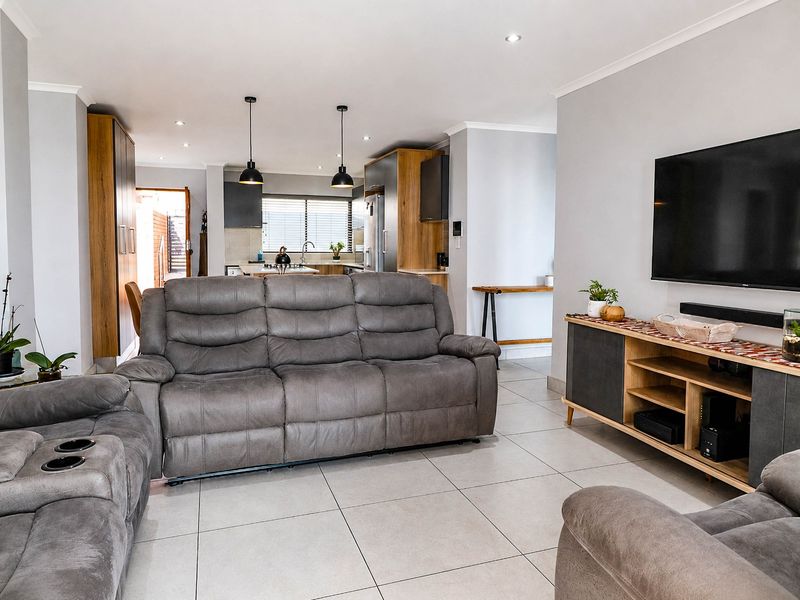 Spacious open-plan living area featuring modern tiled floors, recessed lighting, and a well-appointed kitchen with contemporary cabinetry and island.