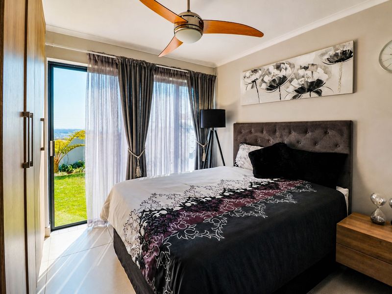 A well-maintained bedroom featuring built-in cupboards, a ceiling fan, and a sliding glass door providing direct access to the garden.