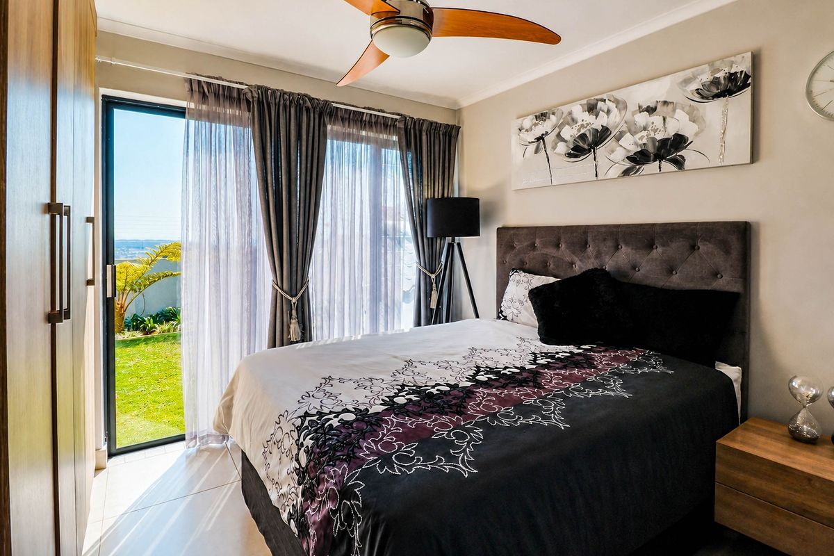 A well-maintained bedroom featuring built-in cupboards, a ceiling fan, and a sliding glass door providing direct access to the garden.