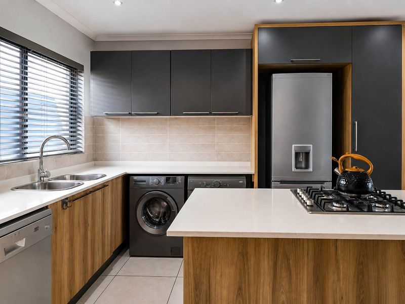 Modern kitchen featuring wood-grain and charcoal cabinetry, quartz countertops, a gas hob, and integrated appliance housing with a clean, contemporary finish.