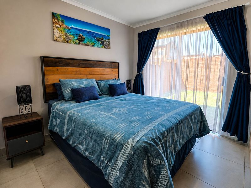 A well-maintained bedroom featuring tiled flooring and a large sliding glass door providing direct access to the rear garden area.