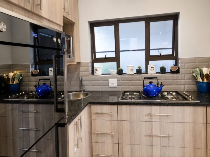 Modern kitchen featuring wood-finish cabinetry, granite countertops, subway tile backsplash, and integrated stainless steel appliances.