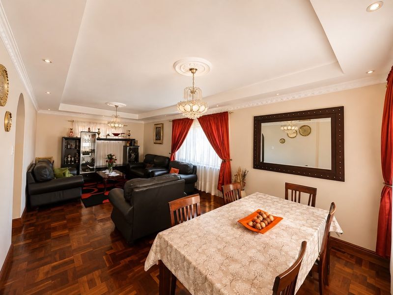 Spacious open-plan living and dining area featuring rich parquet flooring, elegant crown molding, recessed ceilings, and classic crystal chandeliers.