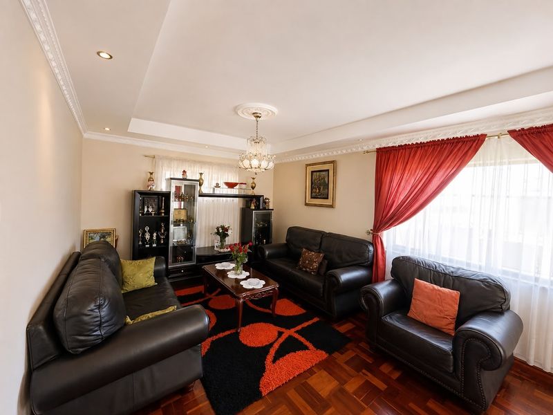 A well-maintained living room featuring classic parquet flooring, decorative ceiling cornices, and recessed lighting, providing a warm and traditional atmosphere.