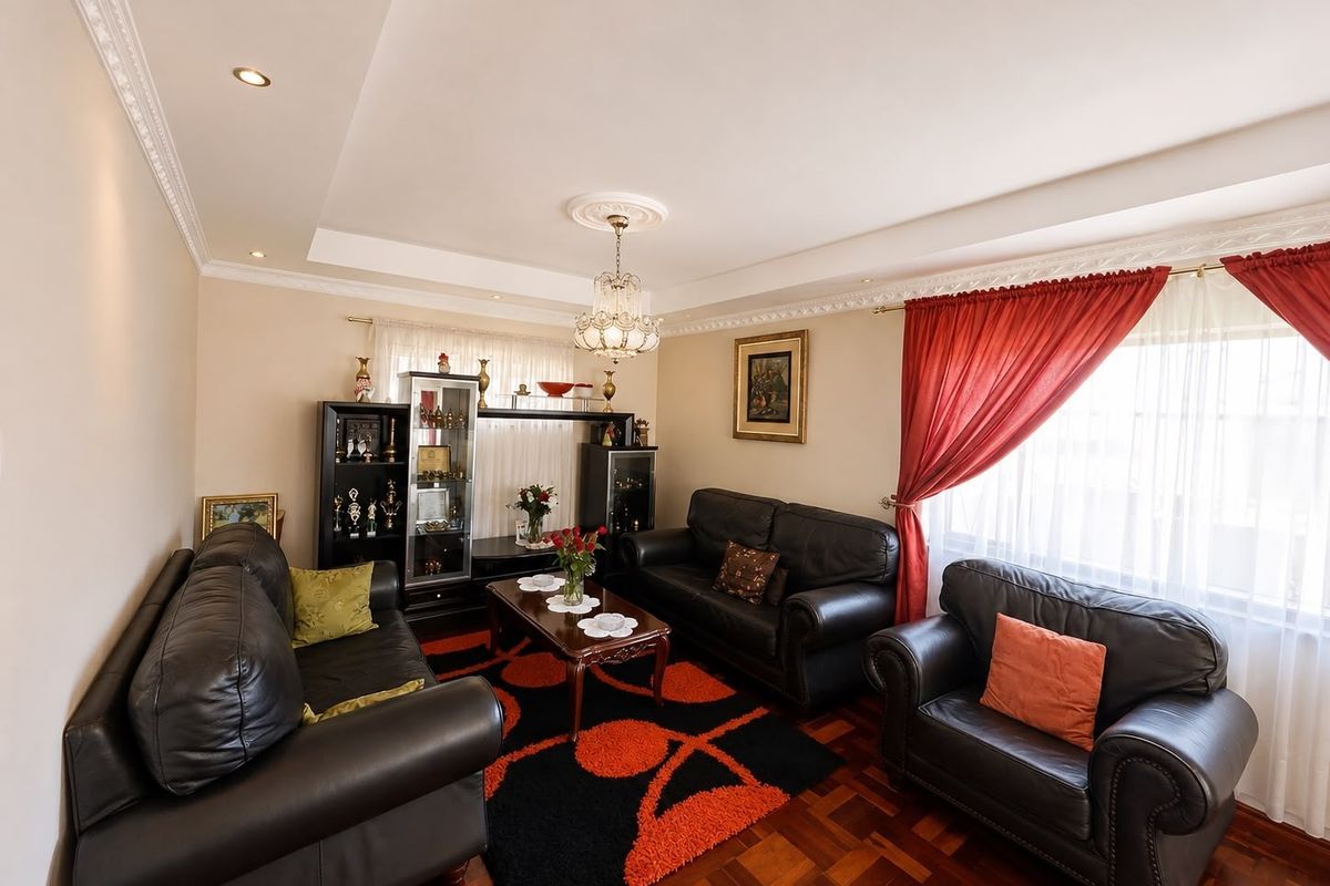 A well-maintained living room featuring classic parquet flooring, decorative ceiling cornices, and recessed lighting, providing a warm and traditional atmosphere.