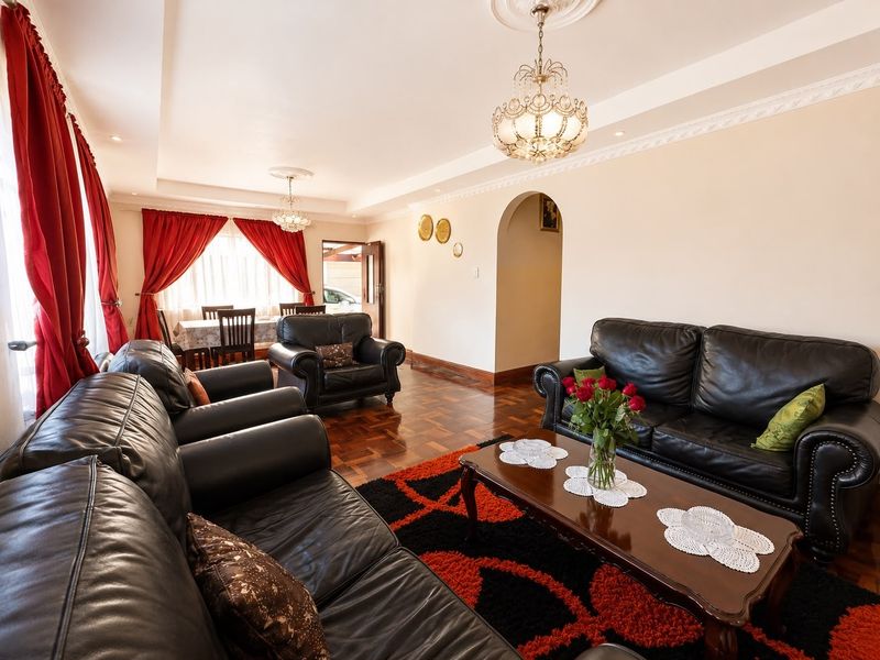Spacious living room featuring classic parquet flooring, decorative ceiling cornices, and elegant crystal chandeliers, creating a warm and traditional atmosphere.
