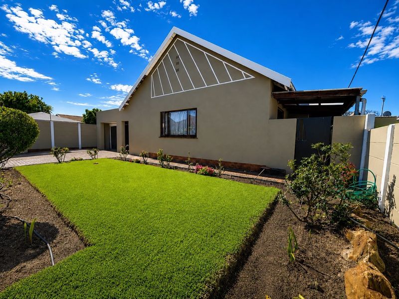 A well-maintained front exterior view of the house featuring a neat lawn, paved driveway, and a gabled roof structure.