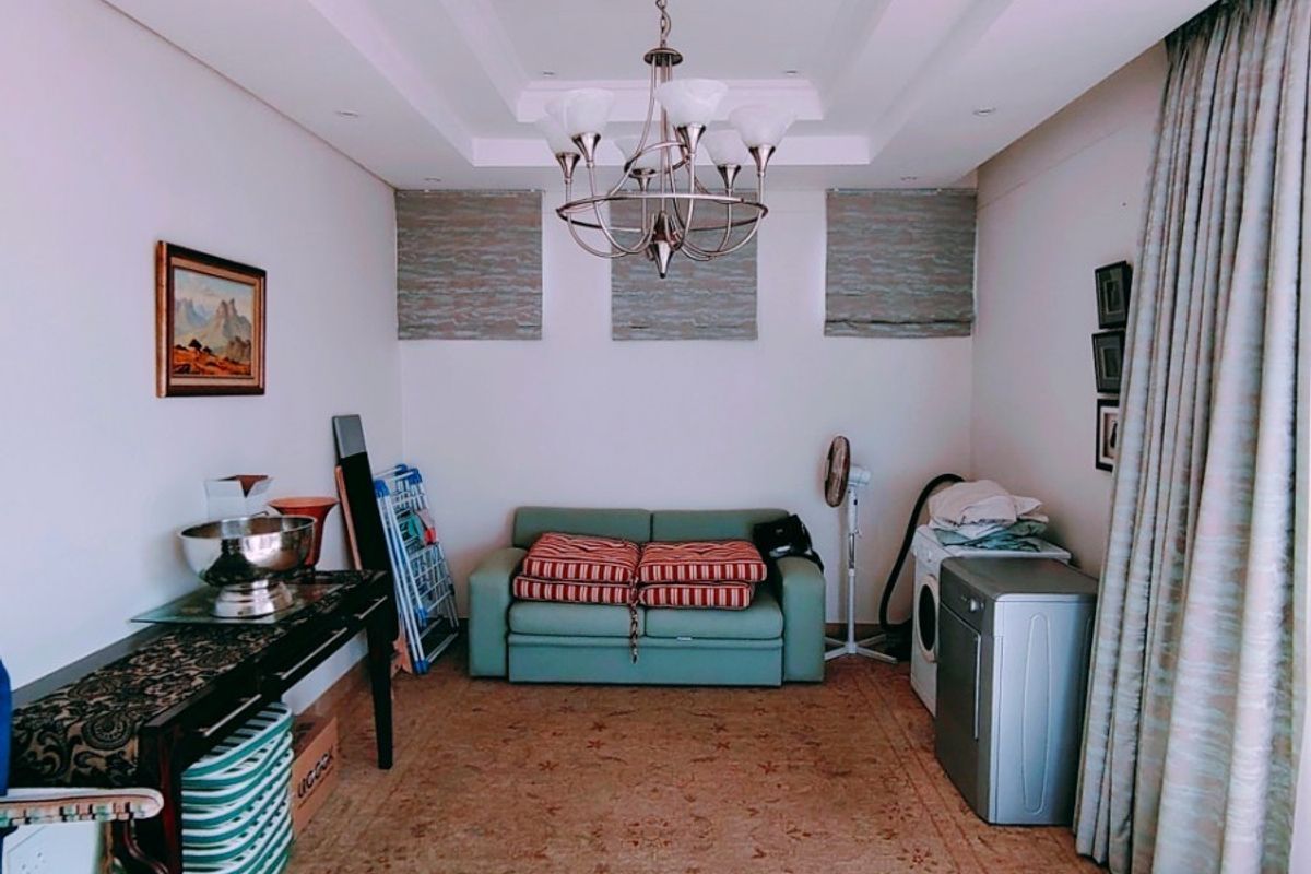 A living area featuring a recessed ceiling with cove lighting, roman blinds, and full-length curtains, offering a versatile space for relaxation.