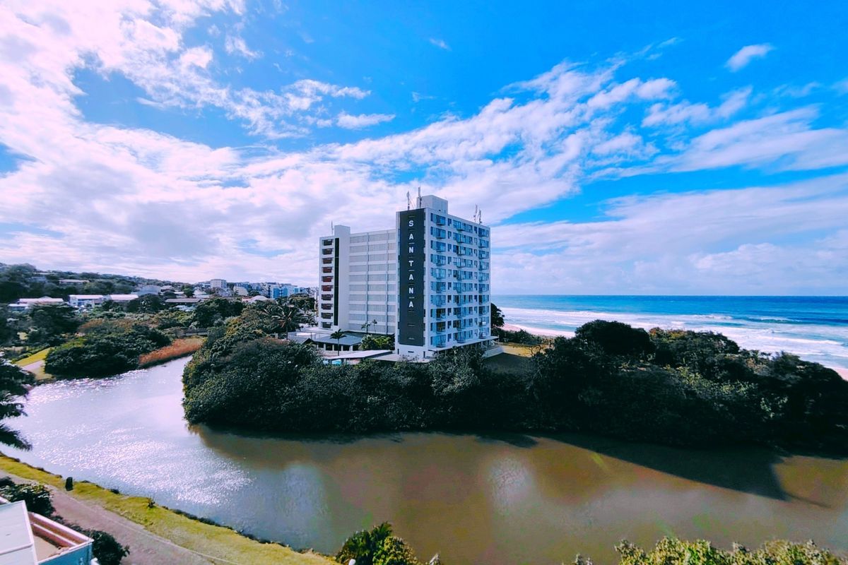 Aerial view of the Santana apartment building situated on a scenic riverfront location adjacent to the coastline.